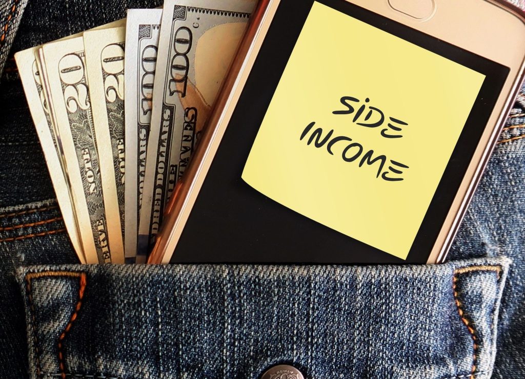 Cash dollars money and mobile phone in jean pocket with note written SIDE INCOME, concept of earning extra cash from side job , side hustle or make more income from online business